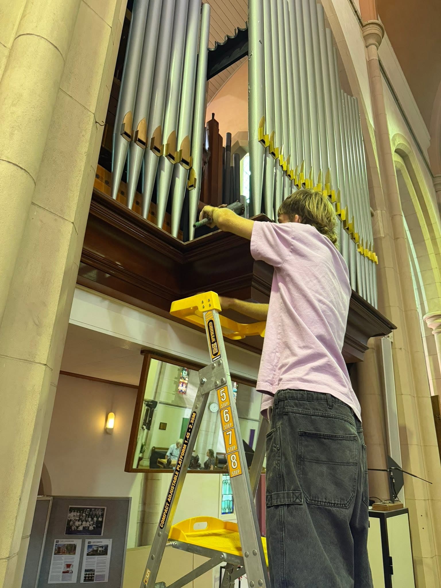 A Pierce Pipe Organs craftsperson working on pipework high in the organ case at St Luke's Anglican Church, Toowoomba